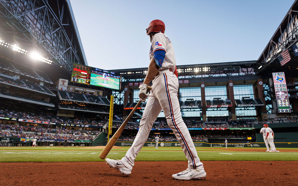 A Texas Ranger baseball player wearing a batting helmet and running on the baseball field.